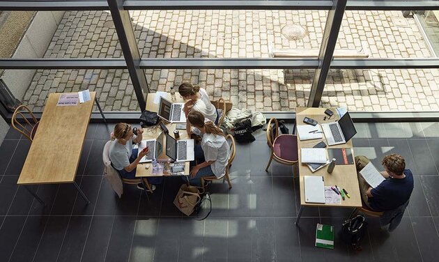 tre kvinnliga studenter med långt hår pluggar på SOL. Vid bordet bredvid sitter en manlig student. 