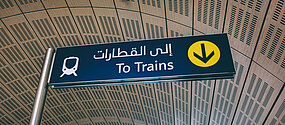 Vägskylt som visar vägen till tågen både på engelska och modern arabiska