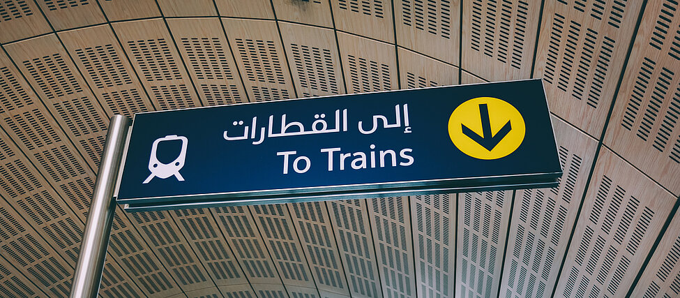 Vägskylt som visar vägen till tågen både på engelska och modern arabiska