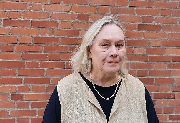 Porträtt av Wibeberg med tegelvägg bakom.