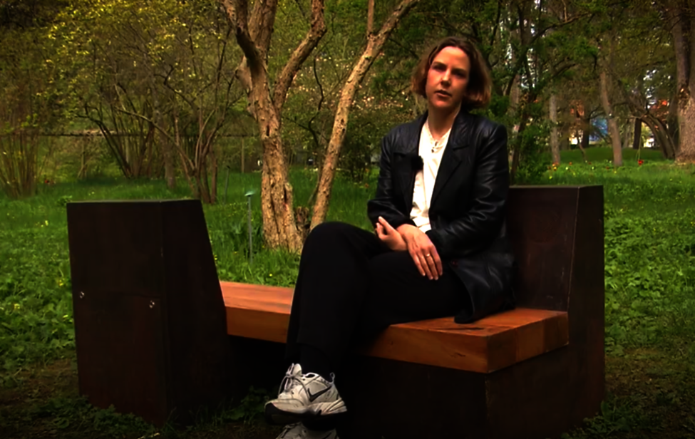 Konstnären Jonna Hägg sittande på ljudbänken i Botaniska trädgården. Foto: Karsten Runerheim