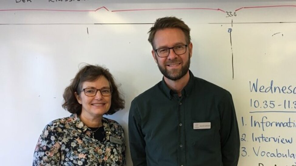 Forskarna Marie Källkvist och Henrik Gyllstad poserar framför en whiteboard i ett klassrum..