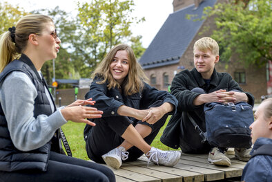 Four students are sitting outside LUX.